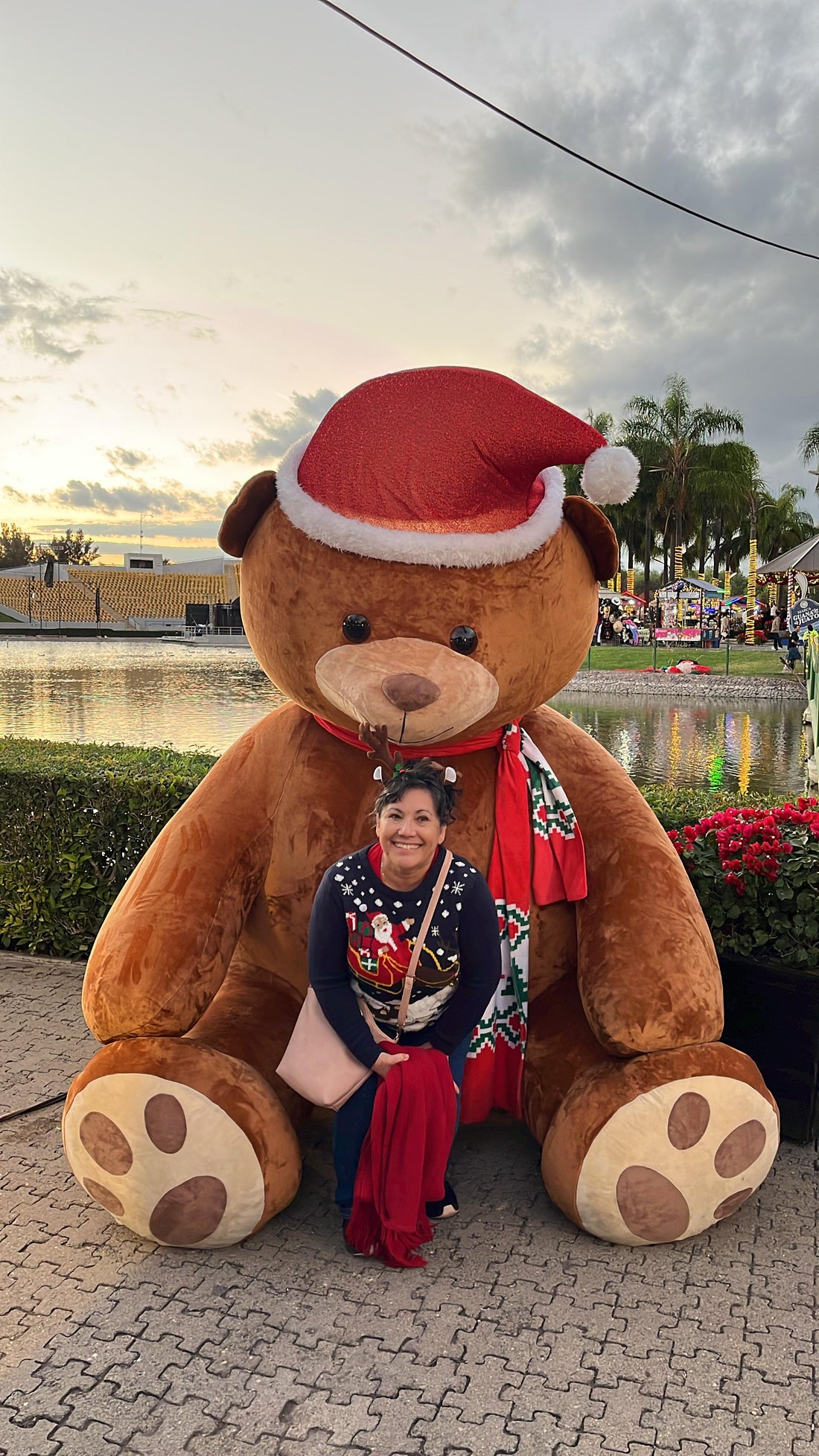 Lupita Cline sitting on the lap of a huge teddy bear with a Santa Claus hat
