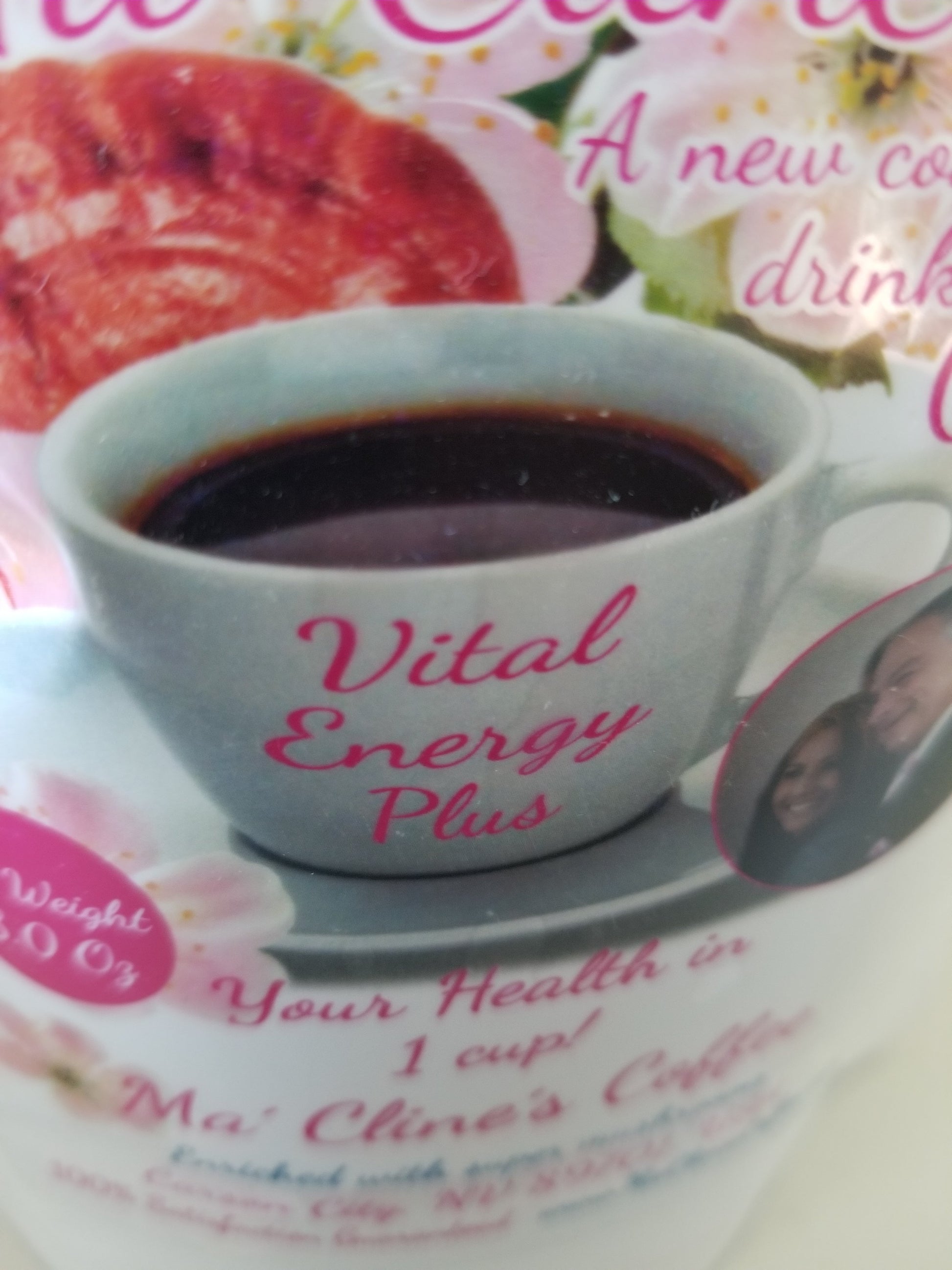 Close up of the front label of Vital Energy Plus, with a white cup and saucer of dark coffee, labeled on the cup Vital Energy Plus. The background contains a red reishi Ganoderma mushroom and pink cherry blossoms. 