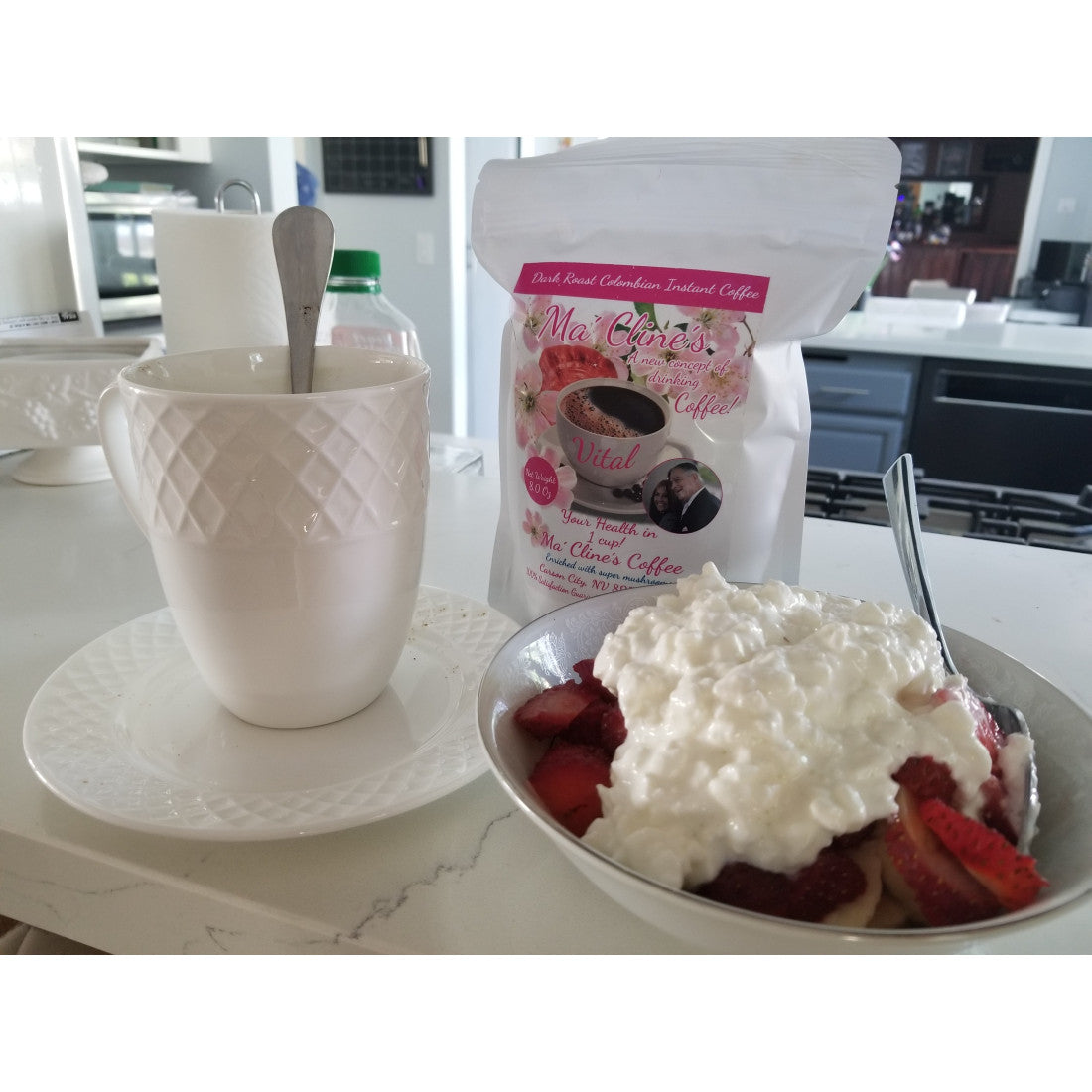 White coffee cup on saucer with spoon protruding from cup, ready to make coffee. On counter in contemporary  kitchen with bag of delicious Ma' Cline's Coffee in the background