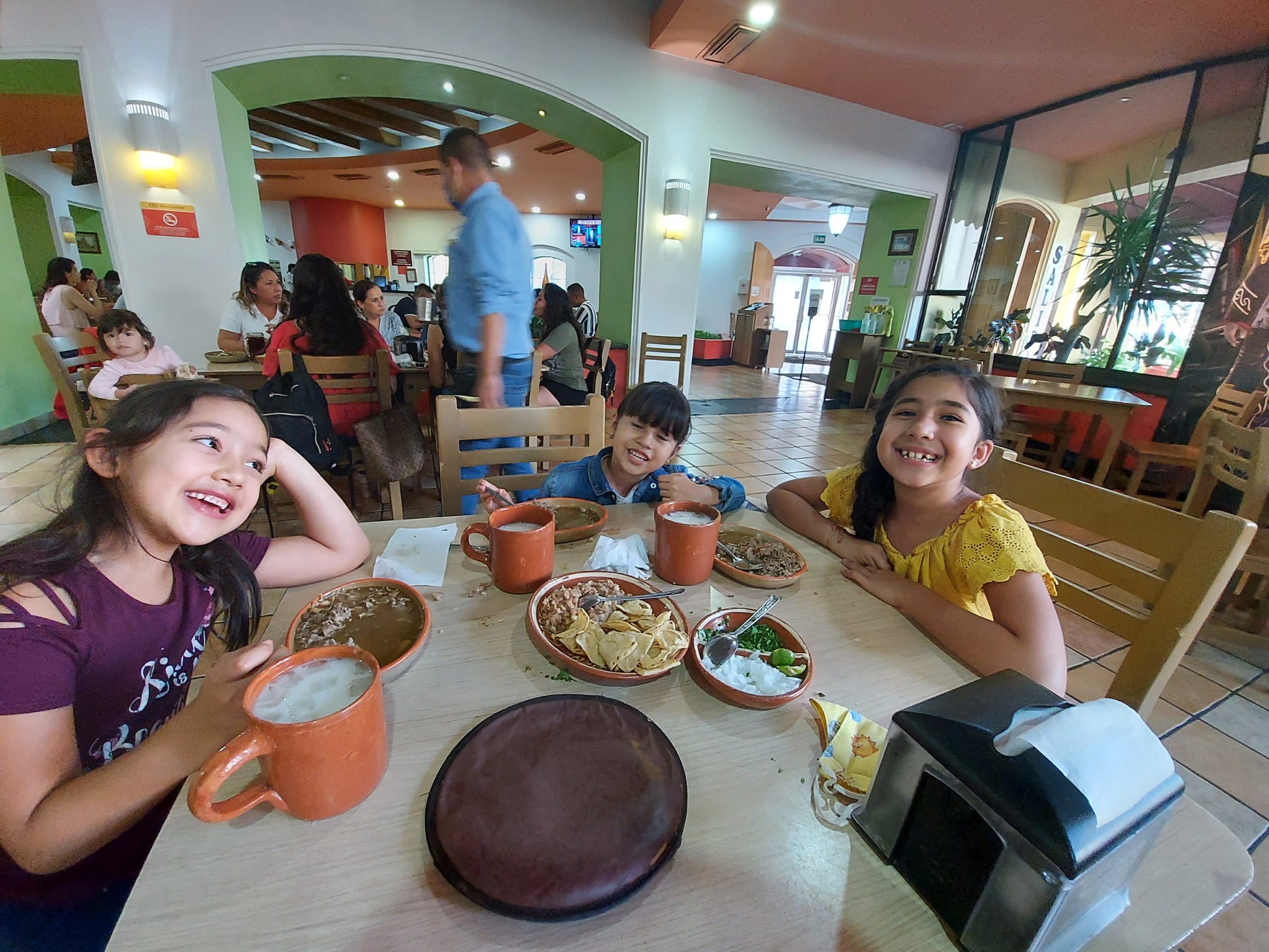 3 smiling, obviously happy, children drinking Ma' Cline's ChocoShroom hot chocolate in a restaurant setting.