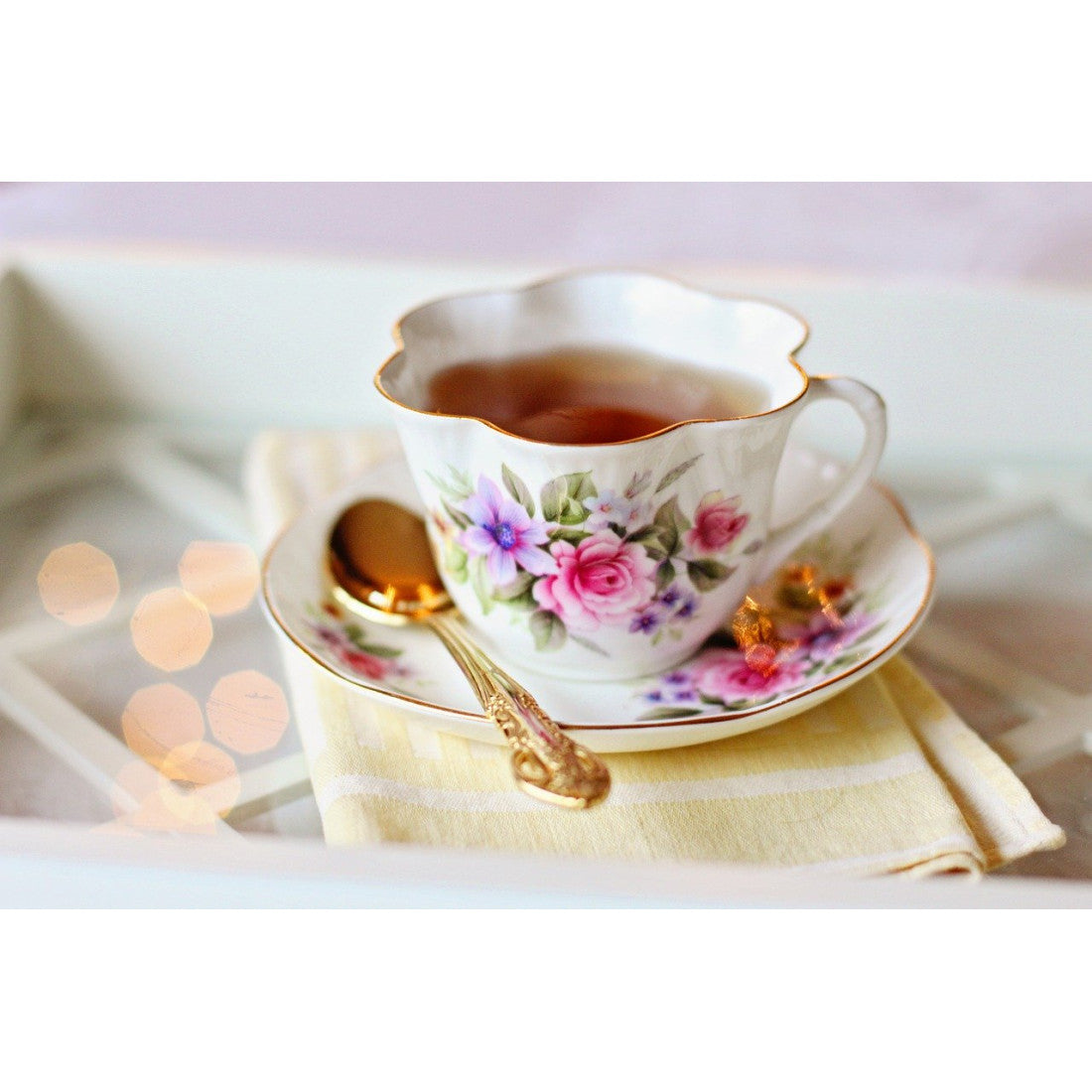 GanoCelebrate Rooibos tea in a pretty fluted china cup and saucer with bright colored flowers as decoration. A gold colored tea spoon rests on the saucer, and all sits on a beige linen napkin. A tea for the most sophisticated occasion.